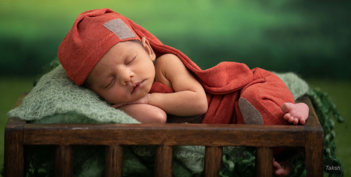 Caucasian baby in Nightcap sleeping next to a mushroom