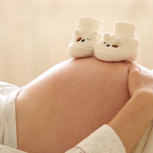 pair of baby booties on a pregnant woman's belly
